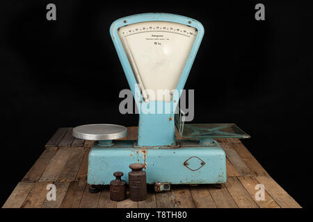The old weight to weigh commodities from the communist era. Shop accessories on a stolen table. Dark background. Stock Photo