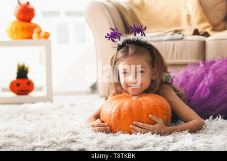 Cute little girl in Halloween costume and with pumpkin at home Stock Photo