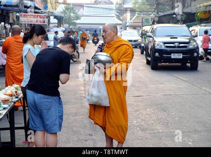 Faithful Thais bow in front of a begging monk, Bangkok, Thailand Stock Photo