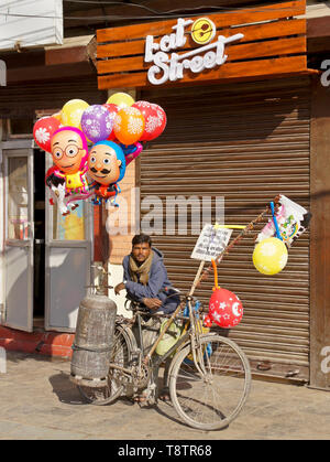 Man selling colorful balloons on street outside fast-food restaurant, Kathmandu, Nepal Stock Photo