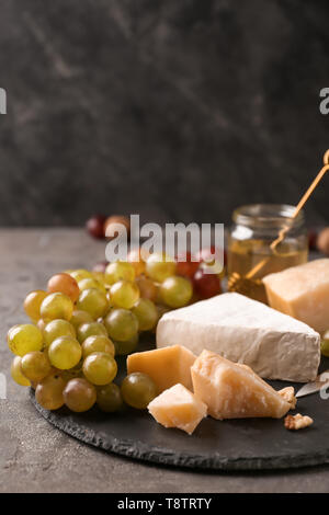 Fresh ripe juicy grapes with cheese on slate plate Stock Photo
