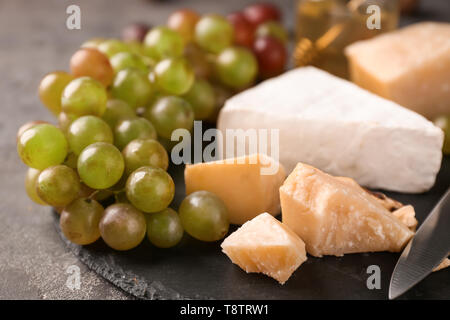 Fresh ripe juicy grapes with cheese on slate plate Stock Photo