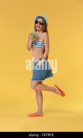 Beautiful woman in beachwear and with tasty summer cocktail on color background Stock Photo