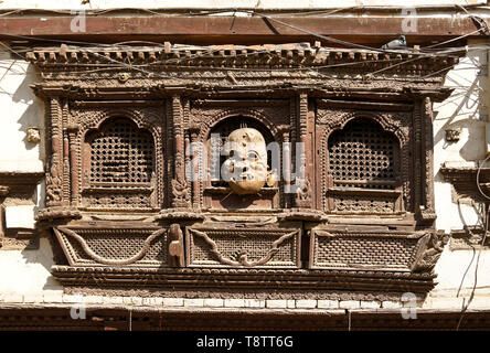 Window with carved wood screen and mask on old building near Durbar Square, Kathmandu, Nepal Stock Photo