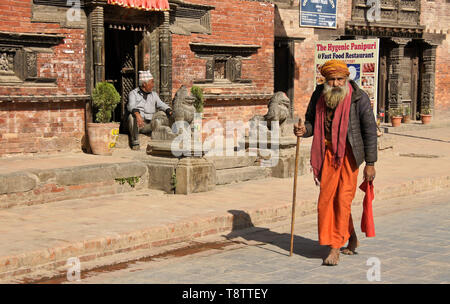 A Hindu sadhu (holy man) walks past old brick buildings on Durbar Square, Patan, Kathmandu Valley, Nepal Stock Photo