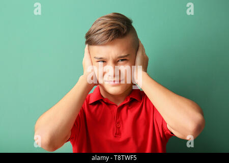 Teenage boy suffering from headache on color background Stock Photo