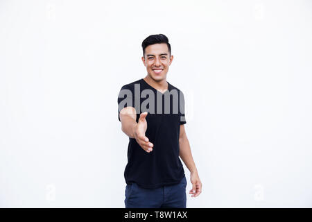 Young handsome man smiling and offering handshake as welcoming. Successful business comunnication concept. Stock Photo