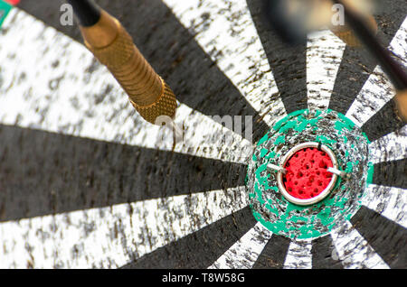 Darts Missing Bullseye on a Worn Out Dartboard. Proper Targeting, Losing Concept. Stock Photo