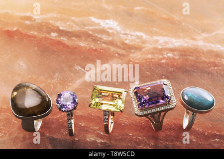 Five different gold rings with precious stones on a marble surface with copy space Stock Photo