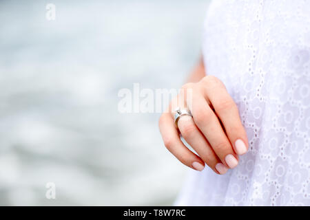 Beautiful woman hand with wedding ring with ocean background. Love concept. Stock Photo