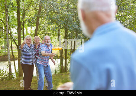 Group of seniors playing frisbee in the park in retirement home in summer Stock Photo