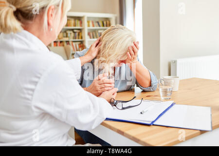 Crying senior patient is comforted by female doctor or nursing wife Stock Photo
