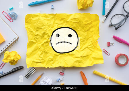 Worker emotion concepts with emoticon face on yellow paper crumpled.Business ideas solution and human performance.Top view Stock Photo
