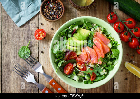 Diet menu, Vegan food. Healthy salad with quinoa, arugula, Tomatoes, Salmon and Avocado on rustic table. Top view flat lay. Stock Photo