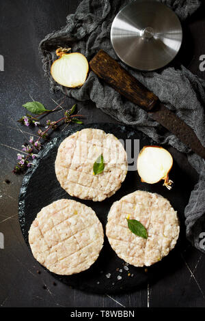 Raw fresh cutlets burger from beef for homemade burgers cooking with spices on black board. Top view. Stock Photo