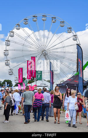 Large crowd of people at busy showground, walking past trade stands, exhibits & towering big wheel - Great Yorkshire Show, Harrogate, England, UK. Stock Photo