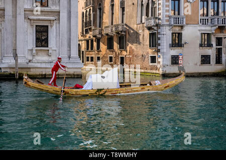 A big mask, decoration for the Venetian Carnival, is getting transported by a gondola at Grand Canal, Canal Grande Stock Photo