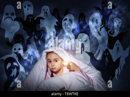 Scared girl with flashlight under blanket Stock Photo