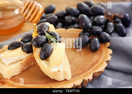 Pouring of honey on sandwich with cheese and grape Stock Photo