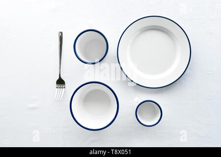 minimalism top or flat lay view of white blue set of dish mug cup fork for dinner on white tablecloth Stock Photo
