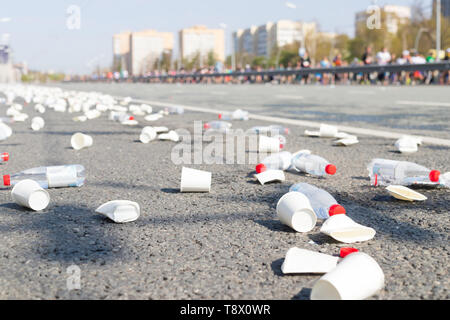 A bunch of plastic cups and empty bottles on the road while a marathon running Stock Photo