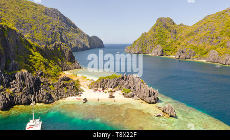 White sandy beach with azure lagoon near rocky islands.Tourists relax on the paradise beach. El Nido Palawan National Park Philippines.Sea surf with tropical islands. Stock Photo