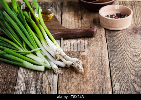 Fresh springtime green onion and garlic on rustic wooden background, plant based food cooking  ingredients Stock Photo