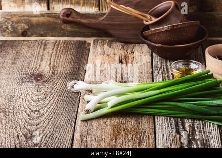 Fresh springtime green onion and garlic on rustic wooden background, plant based food cooking  ingredients Stock Photo