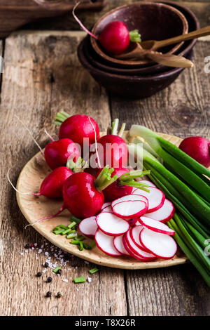 Fresh springtime radishes, green onion and garlic on rustic wooden ...