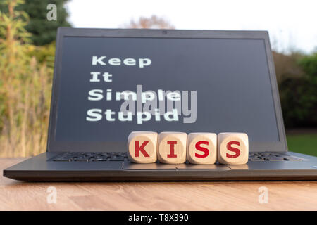 Dice form the abbreviation "KISS". Dice placed on a Notebook. The text "Keep it simple stupid" is written on the display. Stock Photo