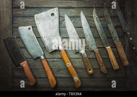 Set of Vintage kitchen knives and meat cleaver on dark wood background. Stock Photo