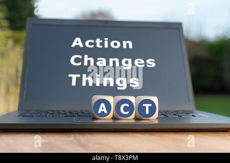 Dice form the abbreviation "ACT". Dice placed on a Notebook. The text "Action changes things" is written on the display. Stock Photo