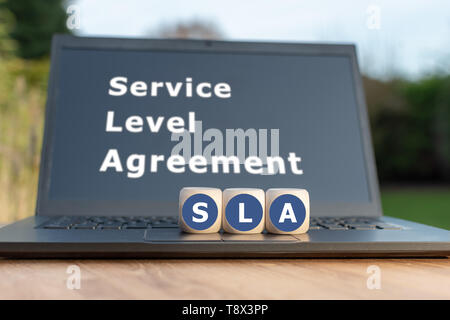 Dice form the abbreviation 'SLA'. Dice placed on a Notebook. The text 'Service level agreement' is written on the display. Stock Photo