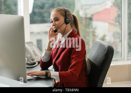 Beautiful female secretary talking through headset in office Stock Photo