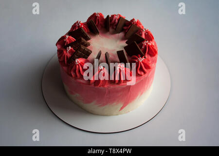 Cherry mousse cake decorated with whipped cream and milk chocolate bars isolated on white background Stock Photo