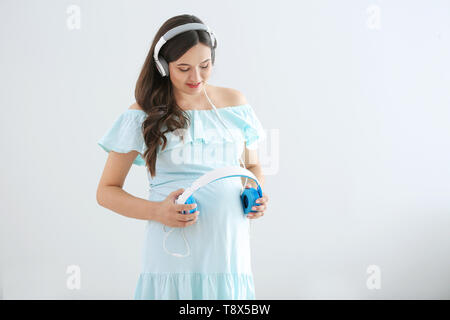 Future Mom holding headphones on her big belly, while her unborn baby  listening pleasant sounds and melody. First Child Anticipation Stock Photo  - Alamy