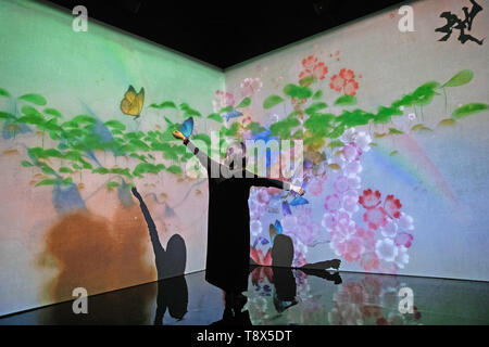 A women interacts with the 'What a Loving and Beautiful World' digital installation at a press preview for 'AI: More Than Human' exhibition at the Barbican Centre in London. The major new exhibition explores the relationship between humans and artificial intelligence. Stock Photo