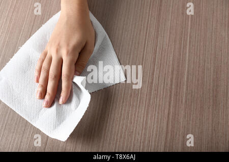 Woman wiping wooden table with paper towel Stock Photo