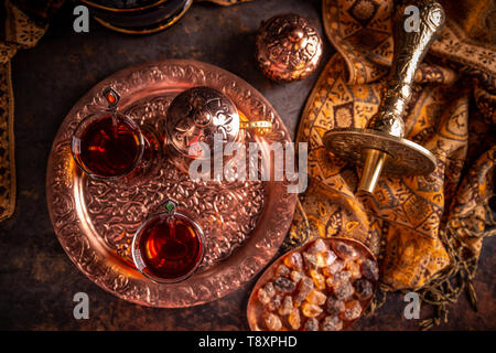 Flat lay of Turkish tea served in authentic glass cup and copper tea kettle Stock Photo