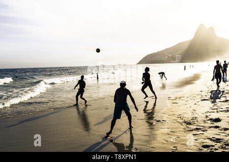 RIO DE JANEIRO, BRAZIL - FEBRUARY 24, 2015: A group of Brazilians playing on the shore of Ipanema Beach, with the famous Dois Irmaos mountain behind them Stock Photo