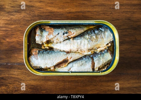 Canned sardines in olive oil on wood background