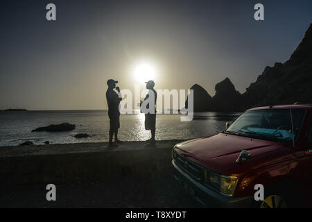 Cape Verde, Cabo Verde archipelago, Brava Island: two men talking near a car and sunset in the background, village of Faja de Agua. Most of the inhabi Stock Photo