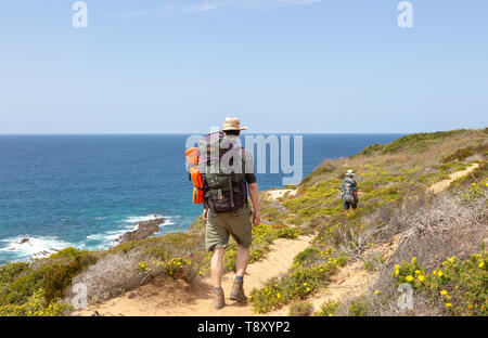 Two people walking the cliff top coastal long distance footpath trail, The Fisherman's Walk or Rota Vicentina,  Odeceixe, Algarve, Portugal Stock Photo