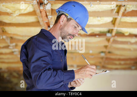 male engineer writing on clipboard at construction site Stock Photo
