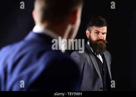 Businessmen look at each other with judgment. Eye contact concept. Business partners on serious faces stand opposite each other. Businessmen, business Stock Photo