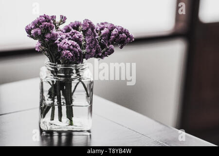 small purple flower in clear glass decorate dark room to be bright blur background Stock Photo