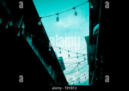 Decorative beautiful  outdoor Party concept idea  string lights bulb blue tine hanging on electricity post in street at night time nobody no people Stock Photo