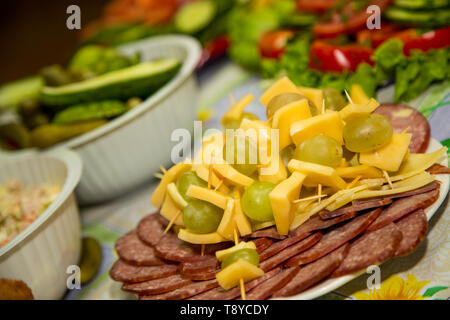 Different kind of sausage and ham are laid out in a plate with cheese and grapes. Stock Photo