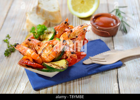 Take away food: Grilled king prawns with mixed vegetables served in a wooden disposable boat Stock Photo