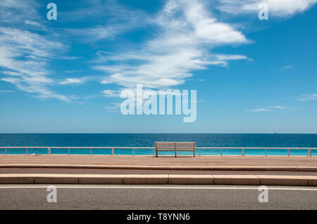 A lonely bench on the shore of the endless blue sea on a Sunny summer day. Minimalism. Stock Photo